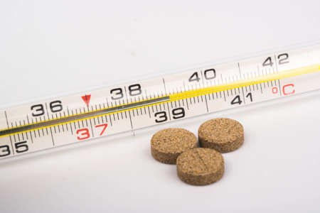 Mercury thermometer shows the temperature of 39 degrees and three tabletsの写真素材