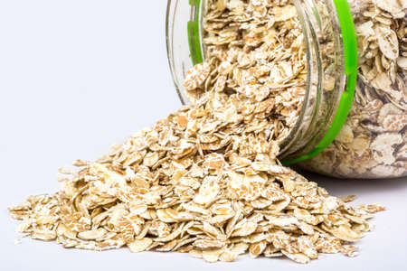 Open plastic jar with are scattered oatmealの写真素材
