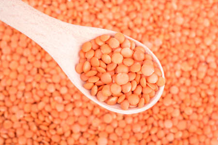 Wooden spoon with red lentils on a background grains