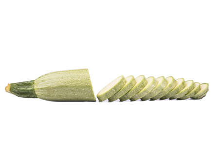 Green vegetable marrow cut into several slices on a white backgroundの写真素材