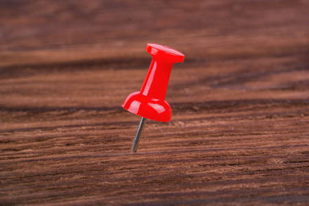 Red pushpin on a brown wooden backgroundの写真素材