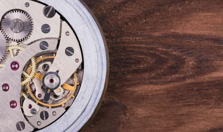 Open old clockwork on a brownwooden background close-up shotの写真素材
