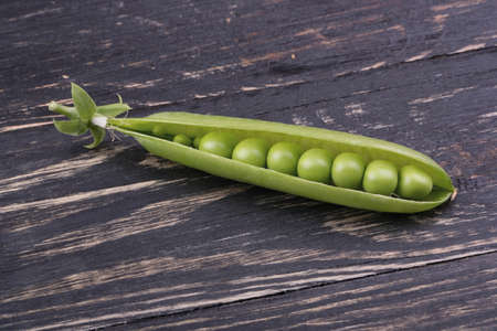 Fresh green peas in open pods with seeds on a wooden backgroundの写真素材