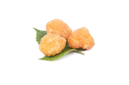 Three fresh yellow raspberries on a leaf on a white background