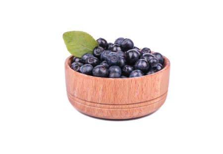 Wooden bowl full of fresh blueberries with leaf isolated on a white background