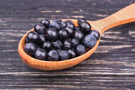 Wooden spoon full of fresh blueberries closeup on wooden backgroundの写真素材