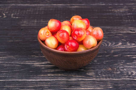 Fresh red and yellow cherries in a bowl on dark wooden backgroundの写真素材