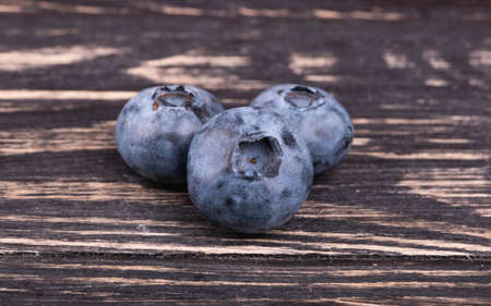 Three blueberries close up on a dark wooden backgroundの写真素材