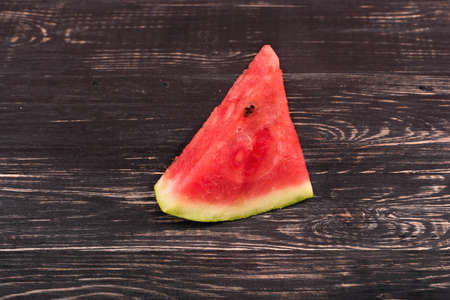 Slice of ripe watermelon on a dark wooden backgroundの写真素材