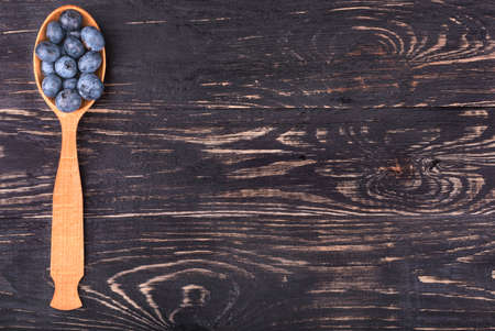 Spoon full of fresh blueberries on a wooden background for recipeの写真素材