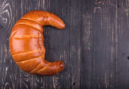 Big croissant with jam on a dark wooden background top viewの写真素材