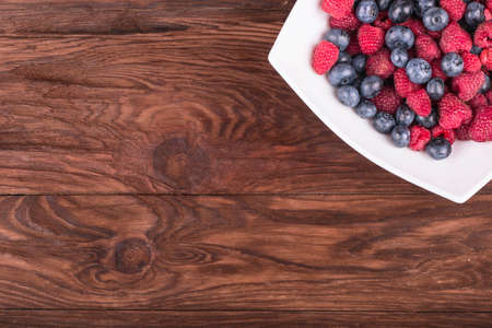 Part plates blueberry and raspberry filling on a brown wooden table top viewの写真素材