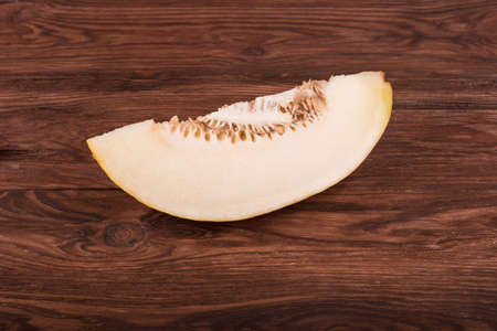 Cut a slice of ripe melon on a brown wooden tableの写真素材