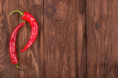 Two fresh red hot chili peppers on a wooden background for textの写真素材