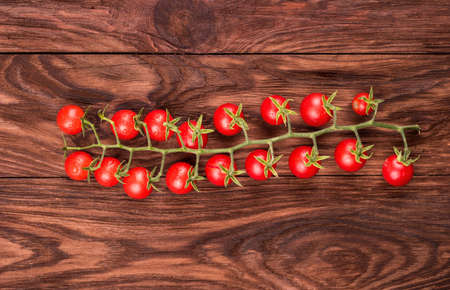 Sprig of fresh red cherry tomatoes on a wooden board close-upの写真素材