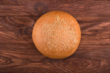 The fluffy bun with sesame seeds on a brown wooden table a top view