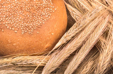 The fluffy bun with sesame seeds and spikelets of wheat closeupの写真素材