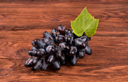 Bunch of fresh grapes with drops and leaf on a wooden backgroundの写真素材