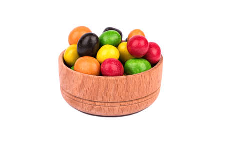 A pile of multi-colored candies in chocolate peanuts in a wooden bowl on a white backgroundの写真素材