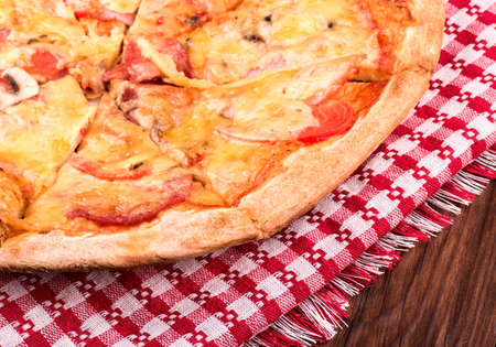 Part fresh pizza with sausage on the tablecloth and the wooden tableの写真素材