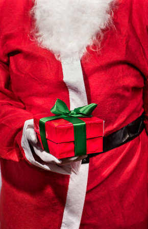 Santa Claus holding in his hand red box bandaged a ribbon with a giftの写真素材