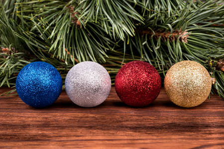 Four different colored Christmas balls on the background of pine branchesの写真素材
