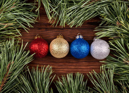 Four different colored Christmas balls surrounded by pine branches top viewの写真素材