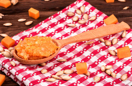 Wooden spoon filled with pumpkin porridge on a kitchen towel on the tableの写真素材