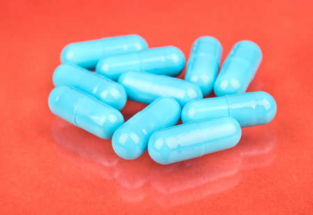 Small pile of blue capsules on a peach background