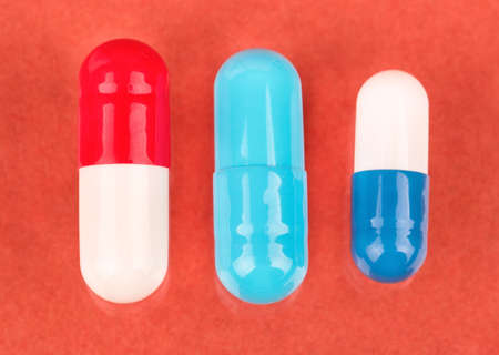 Three various color and shape capsules on a peachy backgroundの写真素材