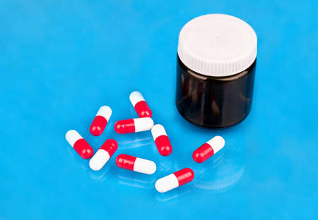 Scattered red-white capsules with a bottle on a blue background