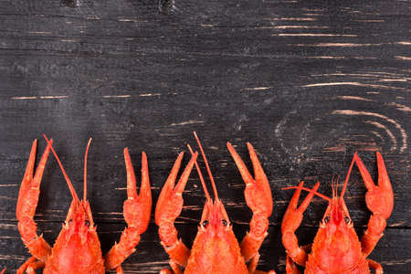 Three red boiled crayfishes lie in the half on a wooden dark backgroundの写真素材