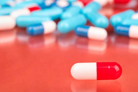 Red white capsule on the background of scattered pillsの写真素材