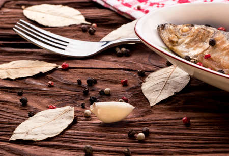 Scattered spices and cooked fried fish on the tableの写真素材