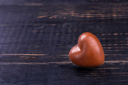 Chocolate candy in the shape of a heart on a wooden background symbolizing valentines dayの写真素材