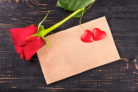 Blank valentine card with red rose and heart on a wooden background