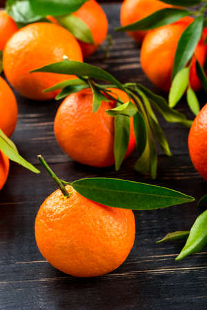 Several fresh tangerine with leaves scattered on the tableの写真素材