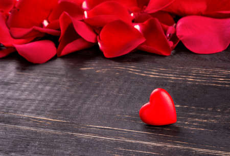 Lonely heart on the background of scattered red rose petalsの写真素材