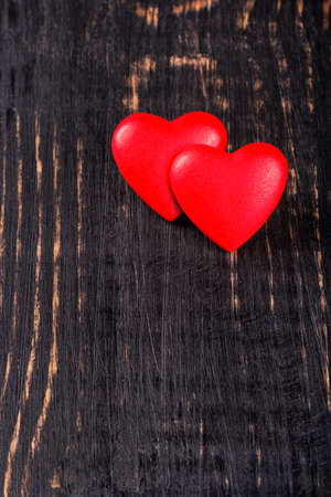 Two hearts on a dark wooden background symbolizing valentines dayの写真素材