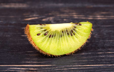 Ripe and juicy kiwi fruit slice on a dark tableの写真素材