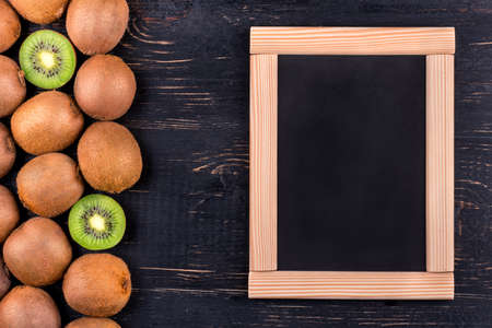 Fresh tropical fruit kiwi with a blank menu on a dark background