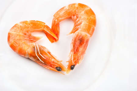 Boiled shrimp in a heart shape on a white plate closeupの写真素材
