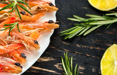 Plate full of boiled shrimps with rosemary and lime on the tableの写真素材