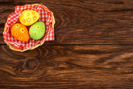 Three Easter eggs in a basket on an empty wooden background a top viewの写真素材