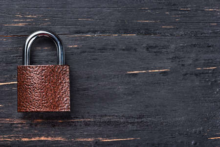 Closed iron lock on an empty wooden backgroundの写真素材