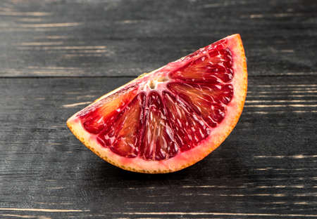 Juicy slice of Sicilian orange fruit on dark wooden backgroundの写真素材