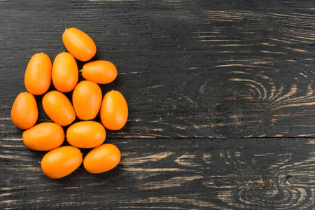 Small bunch of fresh kumquat fruit on a blank wooden backgroundの写真素材