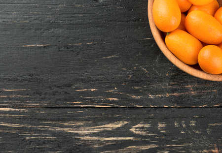 Part bowls filled with fresh fruit kumquat on a blank wooden backgroundの写真素材
