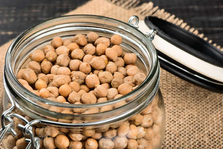 Open full jar of dry chickpeas on a table close-upの写真素材