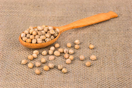 Wooden spoon with dry chickpeas on sackingの写真素材